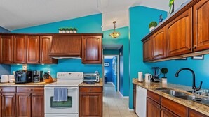 A kitchen with wooden cabinets, a white stove, and a countertop with various appliances. - House with outdoor pool and jacuzzi with canal to the ocean, kayaks, bicycles (Port Charlotte)