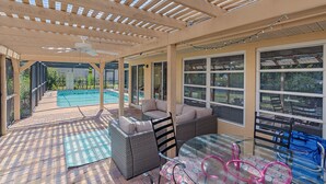 A covered patio area with a pool, outdoor seating, and large windows. - House with outdoor pool and jacuzzi with canal to the ocean, kayaks, bicycles (Port Charlotte)