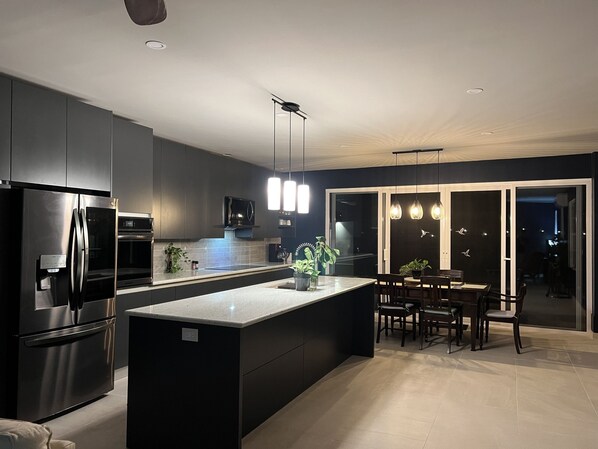 A modern kitchen with a central island, built-in appliances, and pendant lighting.