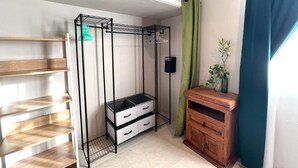 Una habitación compacta con un armario metálico, un mueble de madera y estanterías.