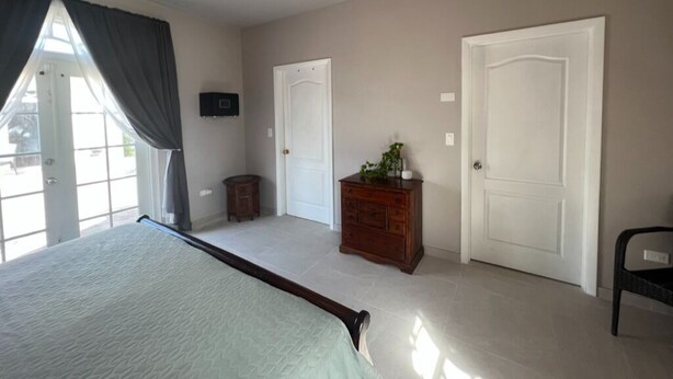 Un dormitorio con cama, ventilador de techo, cómoda y dos puertas.