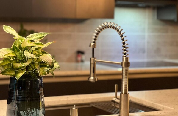 A kitchen with a modern faucet and a potted plant on the counter.