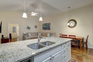 A kitchen with granite countertops, a sink, and a dining area with a table and chairs.