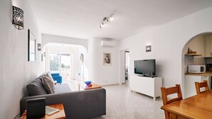 A modern living space with a grey sofa, wooden dining table, and a TV in the background. - Apartment Casa Alegria (Carvoeiro)