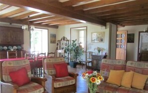 Un salon chaleureux avec des meubles en bois, un coin repas et une cuisine à l’arrière-plan.