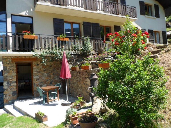 A two-story building with a balcony, outdoor seating area, and potted plants.