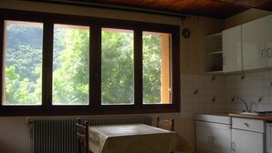 A kitchen with a table and chairs, a window with a view of trees, and white cabinets.
