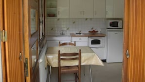 A compact kitchen with white cabinets, a wooden table, and a microwave.