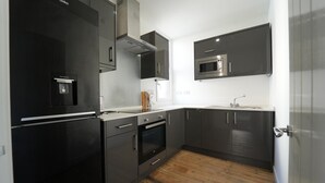 A modern kitchen with a black refrigerator, stainless steel oven, and microwave. - Gorgeous, Comfortable Apartment on the High Street (Merthyr Tydfil)