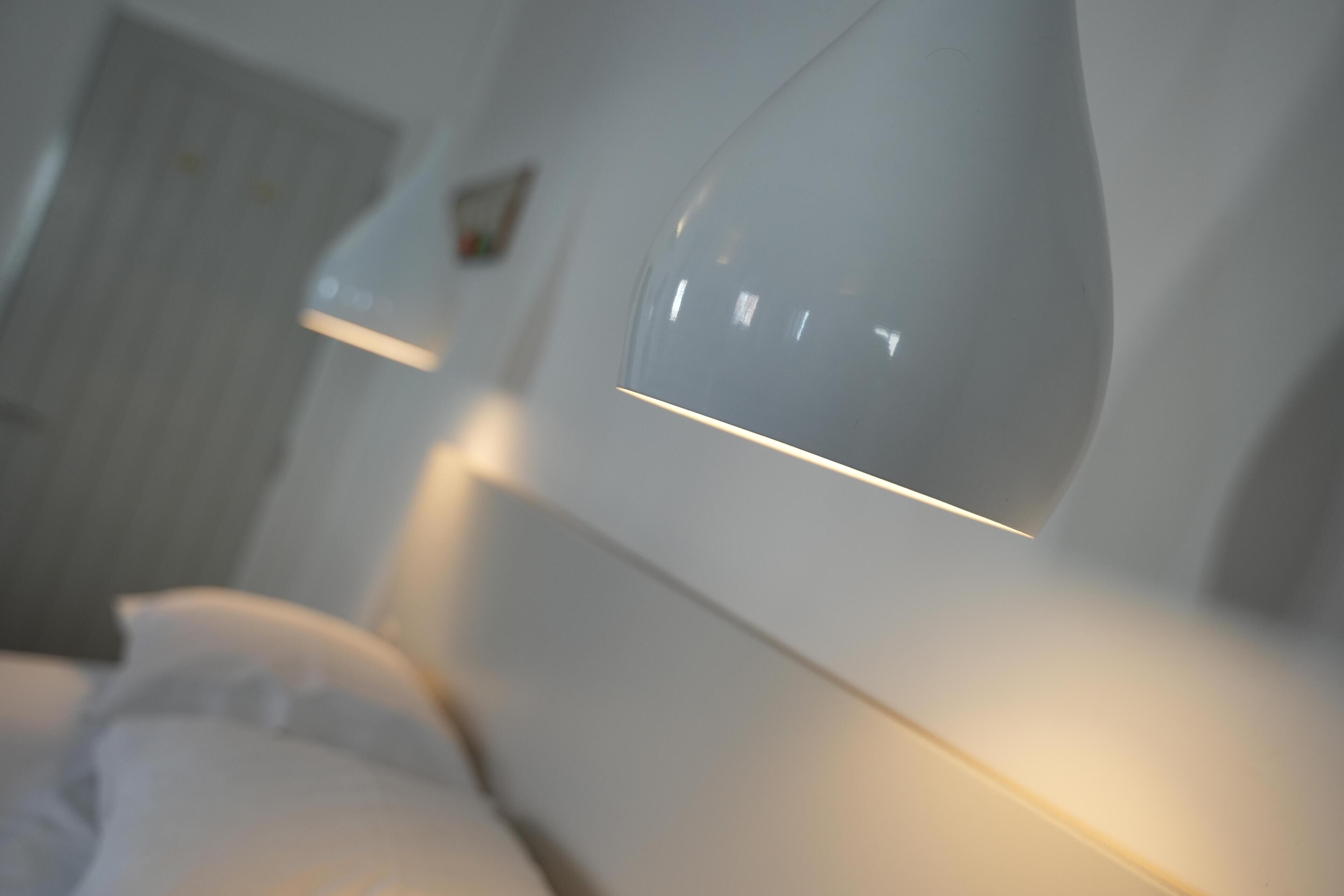 Una habitación de hotel moderna con una cama grande, una mesita de noche y una lámpara fijada a la pared.