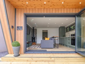 Ein modernes Haus mit einem großen Glasfenster, das in einen Wohnbereich, eine Küche und einen Kamin führt.