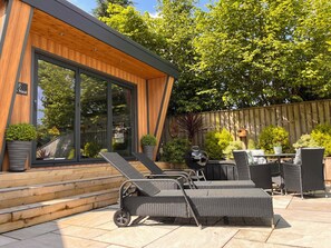 Eine moderne Terrassengrundstück mit Korbmöbeln, einem Grill und einem Holzboden.