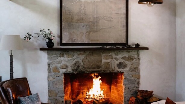 Una sala de estar acogedora con chimenea de piedra, muebles de cuero y una lámpara colgante.