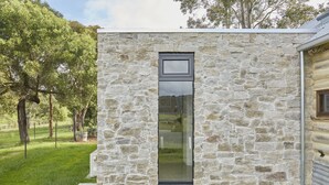 Un edificio de piedra con un ventanal grande, rodeado de césped y árboles.