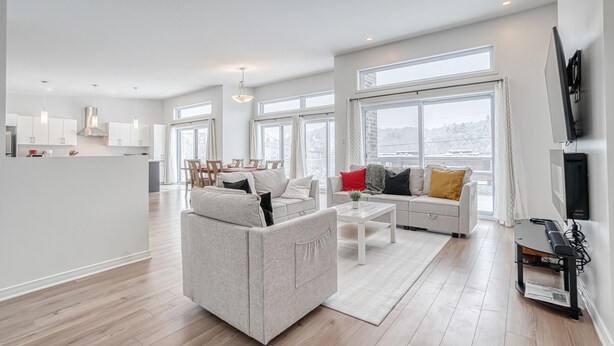 A spacious living area with a sofa, coffee table, and a flat-screen TV. - Modern chalet B (Gatineau)