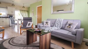 Ein modernes Wohnzimmer mit grauem Sofa, Couchtisch und Essbereich mit weißem Schrank und Stuhl.