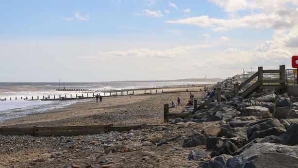 Ein felsiger Strand mit einer hölzernen Promenade, die zu einem Steg führt.