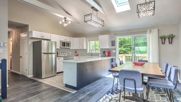 A modern kitchen with a central island, stainless steel appliances, and a dining area with a large table and chairs.