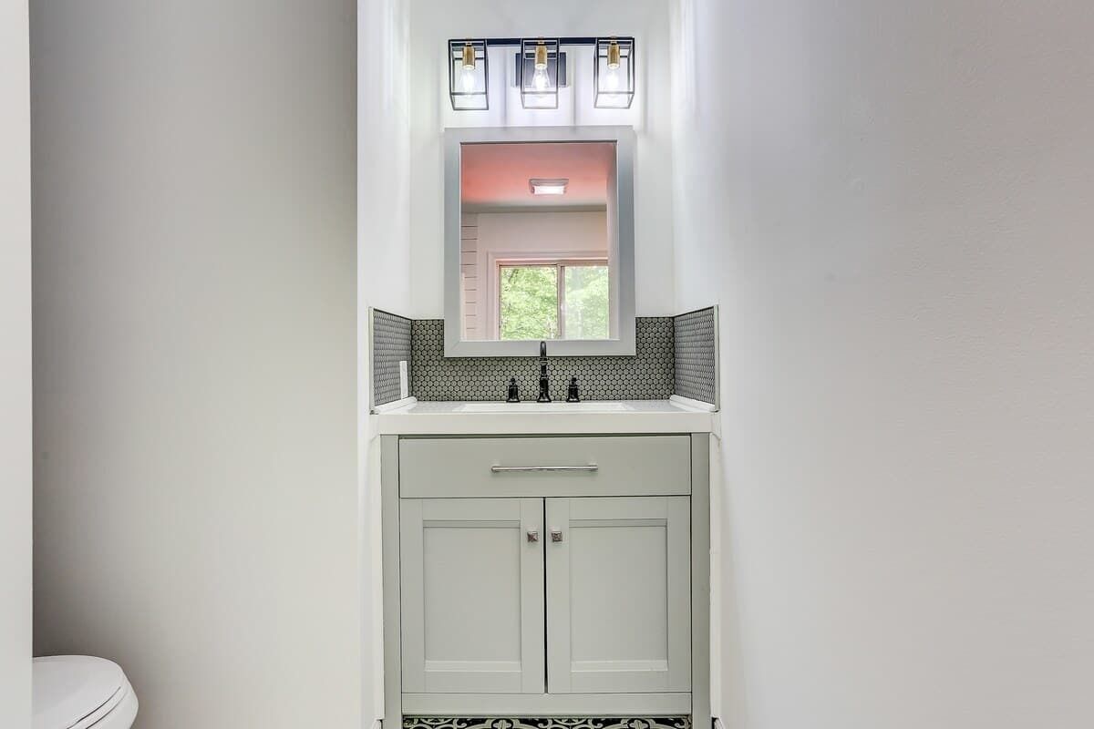 Une salle de bain avec un lavabo blanc, un miroir et des toilettes.