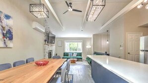 A modern kitchen with a dining area, a ceiling fan, and a large window.