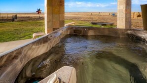 Una bañera de hidromasaje con vistas despejadas del paisaje circundante, que incluye un área con césped y una valla distante.