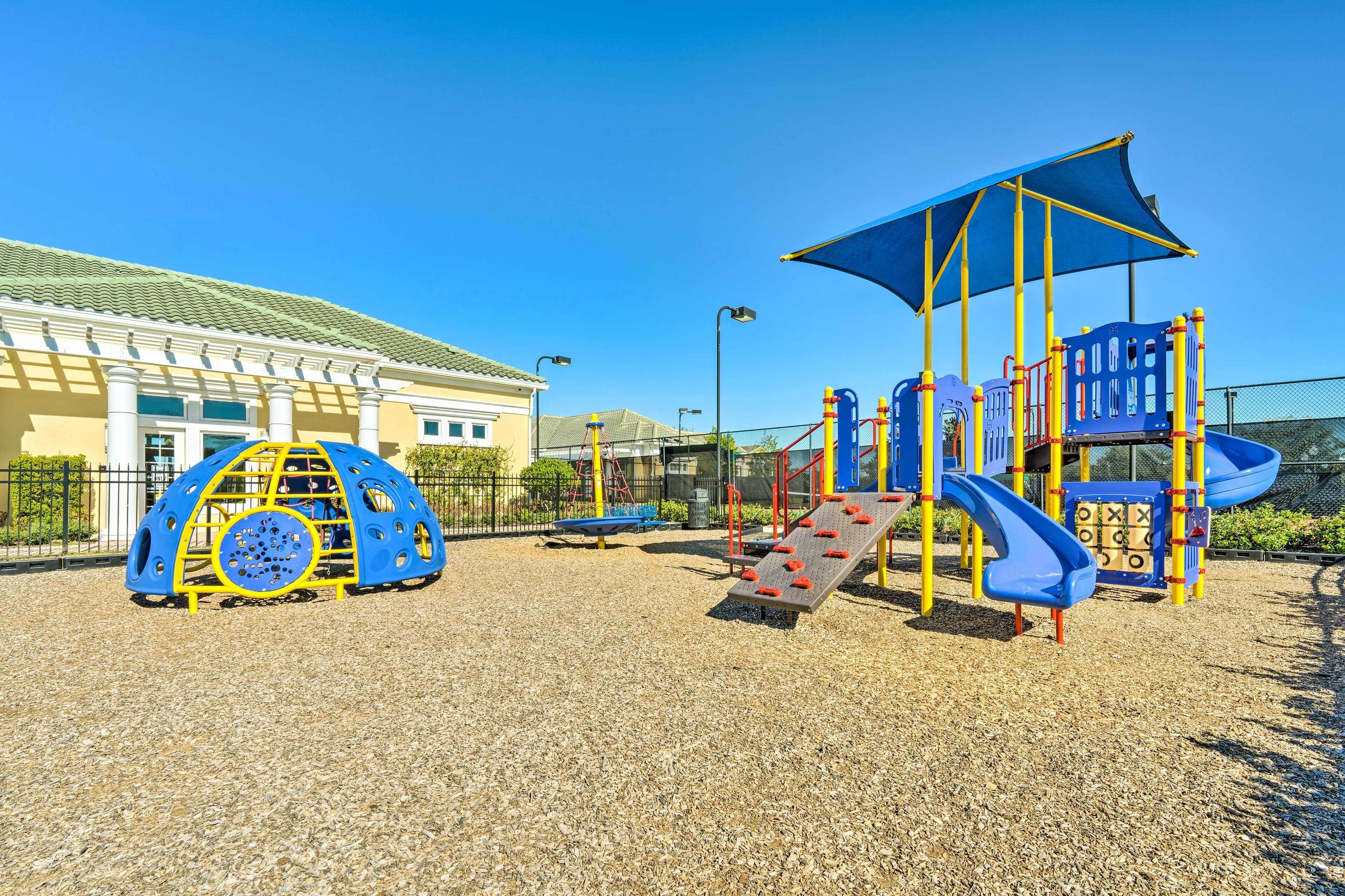 Un parque infantil con una estructura para escalar, toboganes y una zona con sombra.
