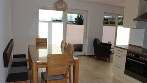 A modern kitchen with a dining area, a built-in oven, and a sliding glass door leading to a balcony.