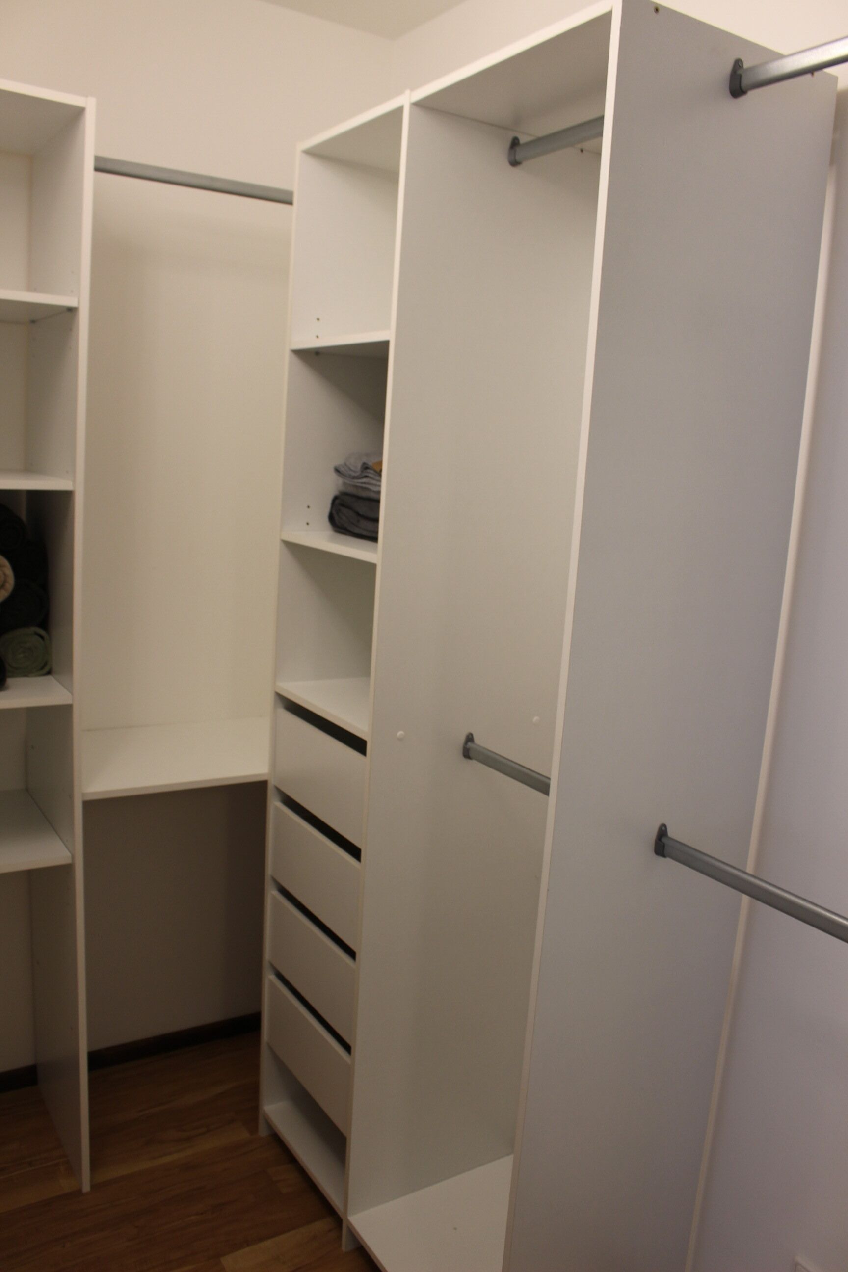 Um closet espaçoso com prateleiras abertas, gavetas e cabideiros.