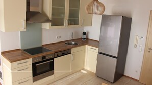 A modern kitchen with a stainless steel refrigerator, a built-in oven, a dishwasher, and a wooden countertop.