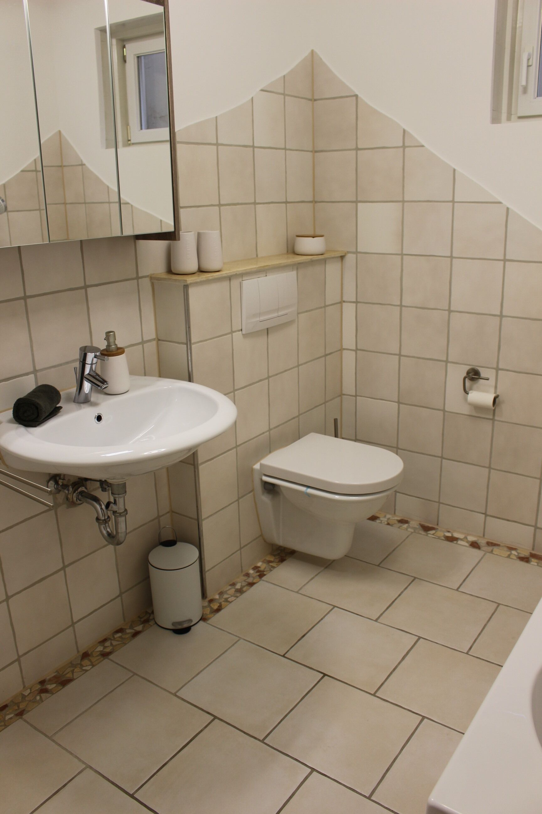 A bathroom with a sink, toilet, and mirror.