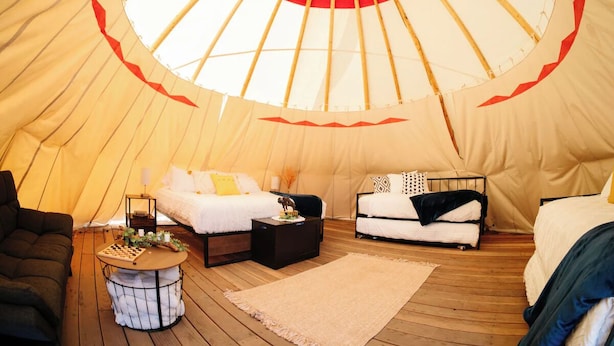 A tent with two beds, a small table, and a sofa. - Yellowstone Family Tipi sleeps 7, w/ 1 king (Island Park)