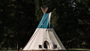 A teepee-style tent with a ladder, two chairs, and a small entrance. - Yellowstone Family Tipi sleeps 7, w/ 1 king (Island Park)