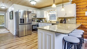 Une cuisine moderne dotée d’appareils électroménagers en acier inoxydable, de plans de travail en granit et d’éléments décoratifs en bois.