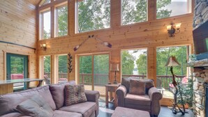 Une cabane en bois spacieuse, dotée d’un grand salon comprenant un canapé, des fauteuils et une table basse.