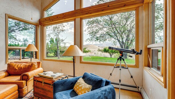 A room with a blue sofa, a leather couch, and a telescope. - Hot Tub, Wineries, Mtn Views: Palisade Home! (Palisade)