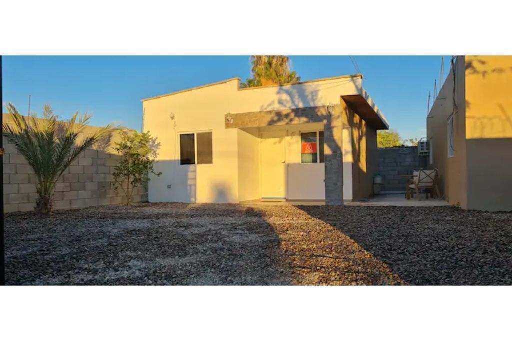 A modern building with a flat roof, a small entrance, and a gravel driveway.