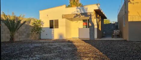 A modern building with a flat roof, a small entrance, and a gravel driveway.