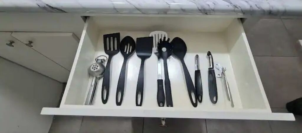 Un cassetto della cucina con diversi utensili, tra cui spatole, una grattugia e un coltello.