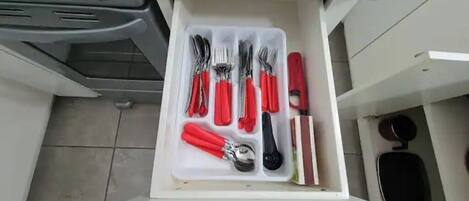 Un cassetto contenente utensili e un coltello con manico rosso.