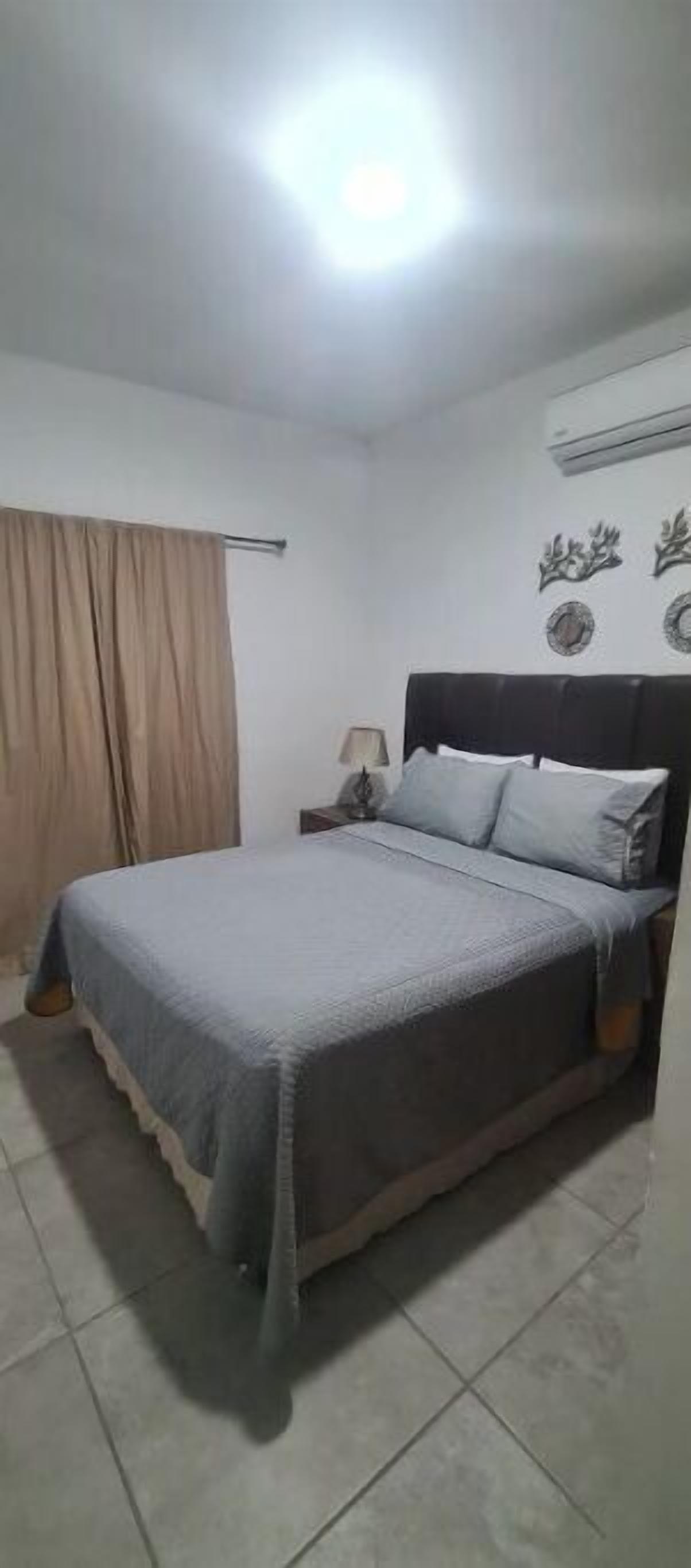 Ein Schlafzimmer mit Bett, Vorhängen, Nachttisch und Wanddekorationen.