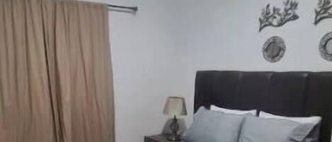 Ein Schlafzimmer mit Bett, Vorhängen, Nachttisch und Wanddekorationen.