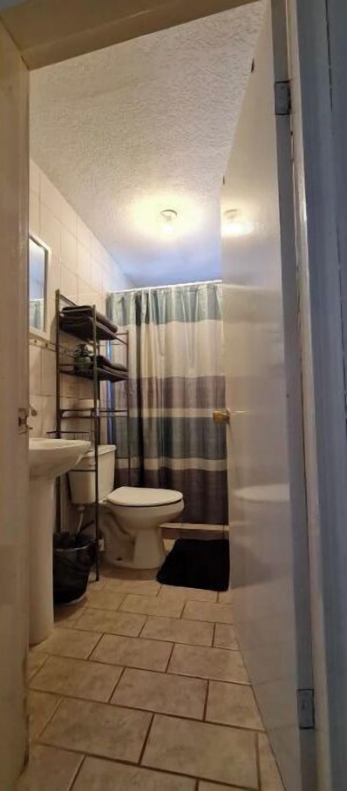 Pieni kylpyhuone, jossa on wc, pesuallas ja suihkutila.