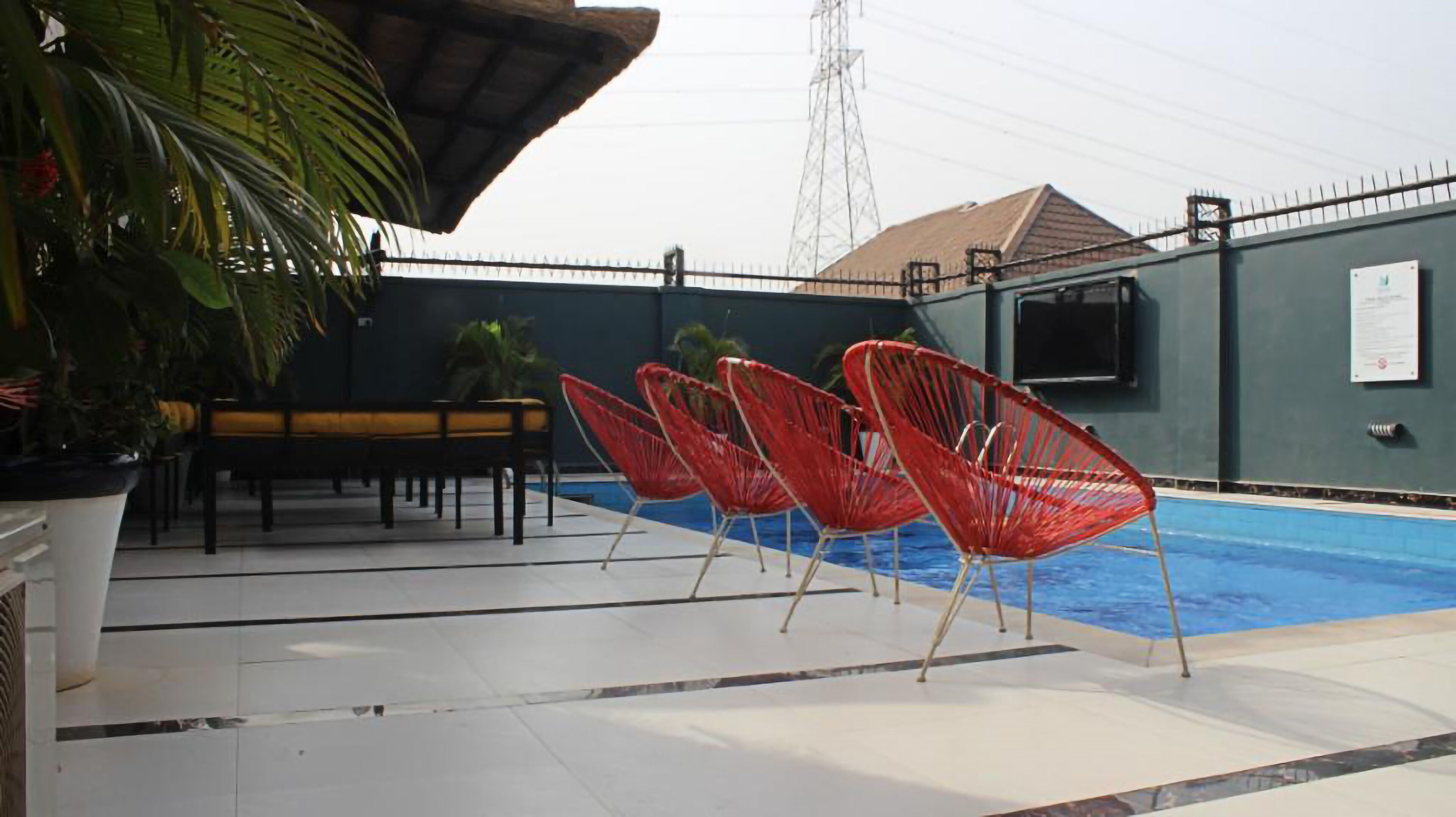 A pool area with red chairs, a bench, and a table.