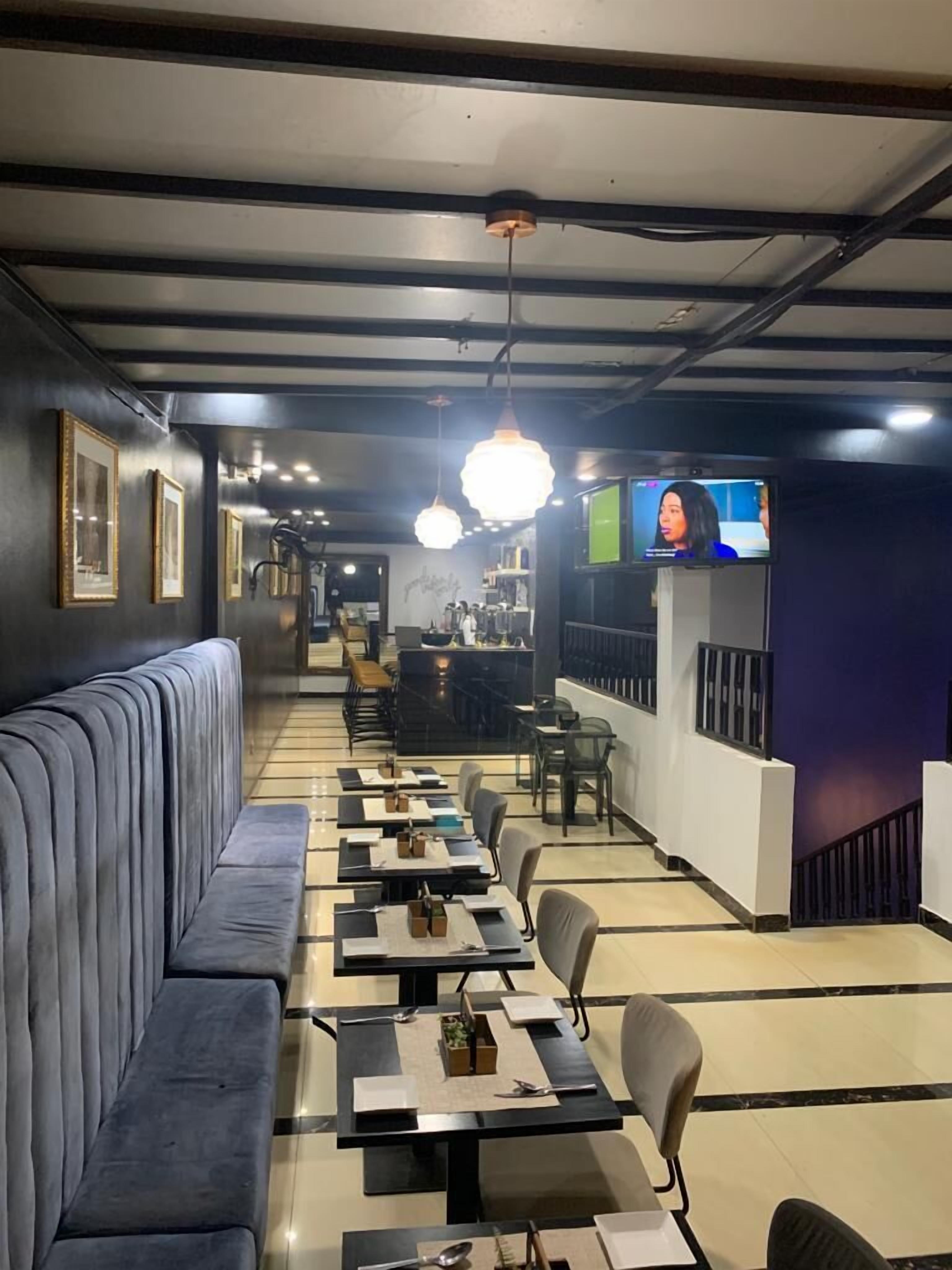 A restaurant with a long counter, booths, and a TV screen.