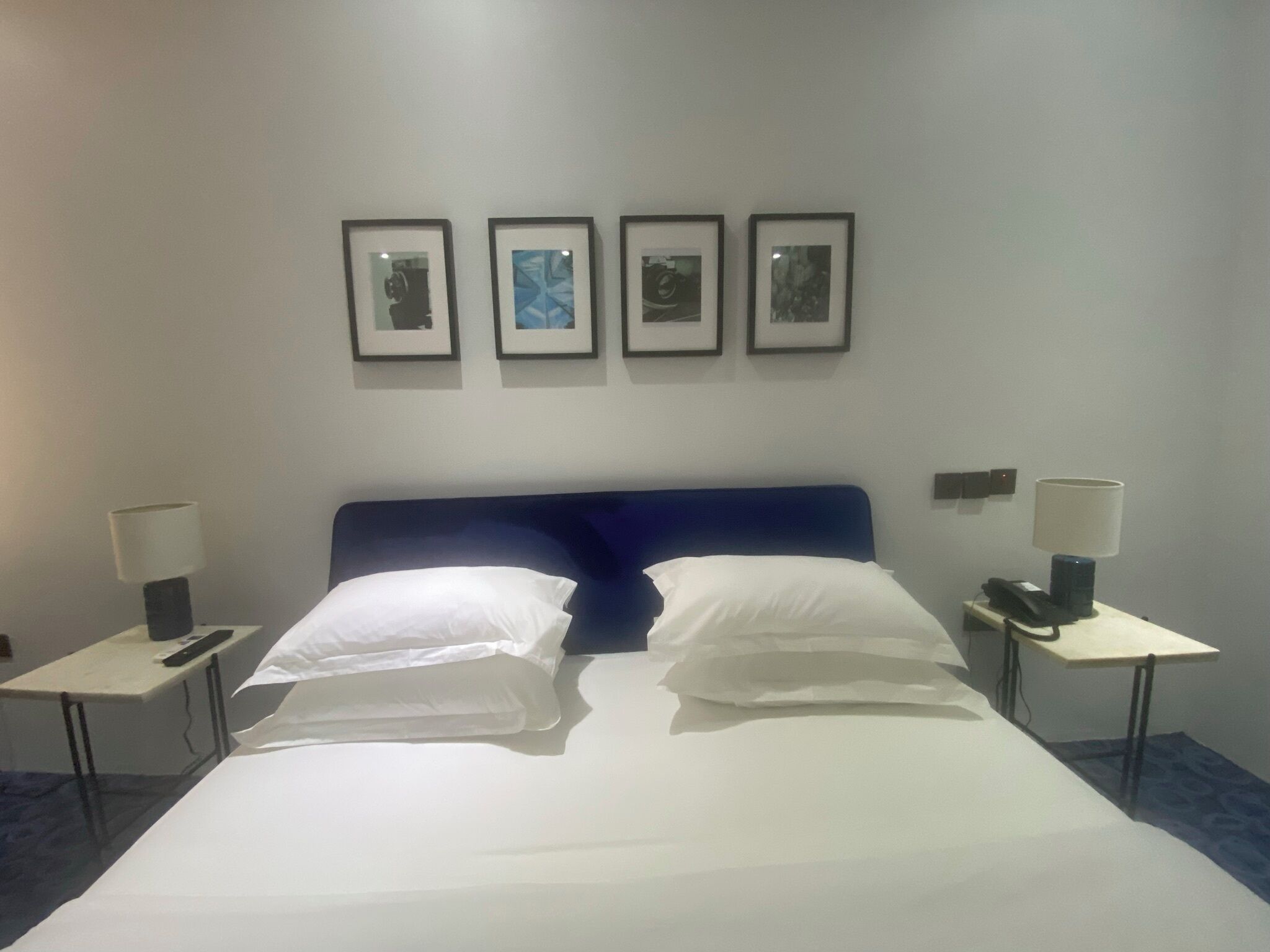 Una habitación de hotel con una cama grande, dos mesitas de noche y un teléfono en la pared.