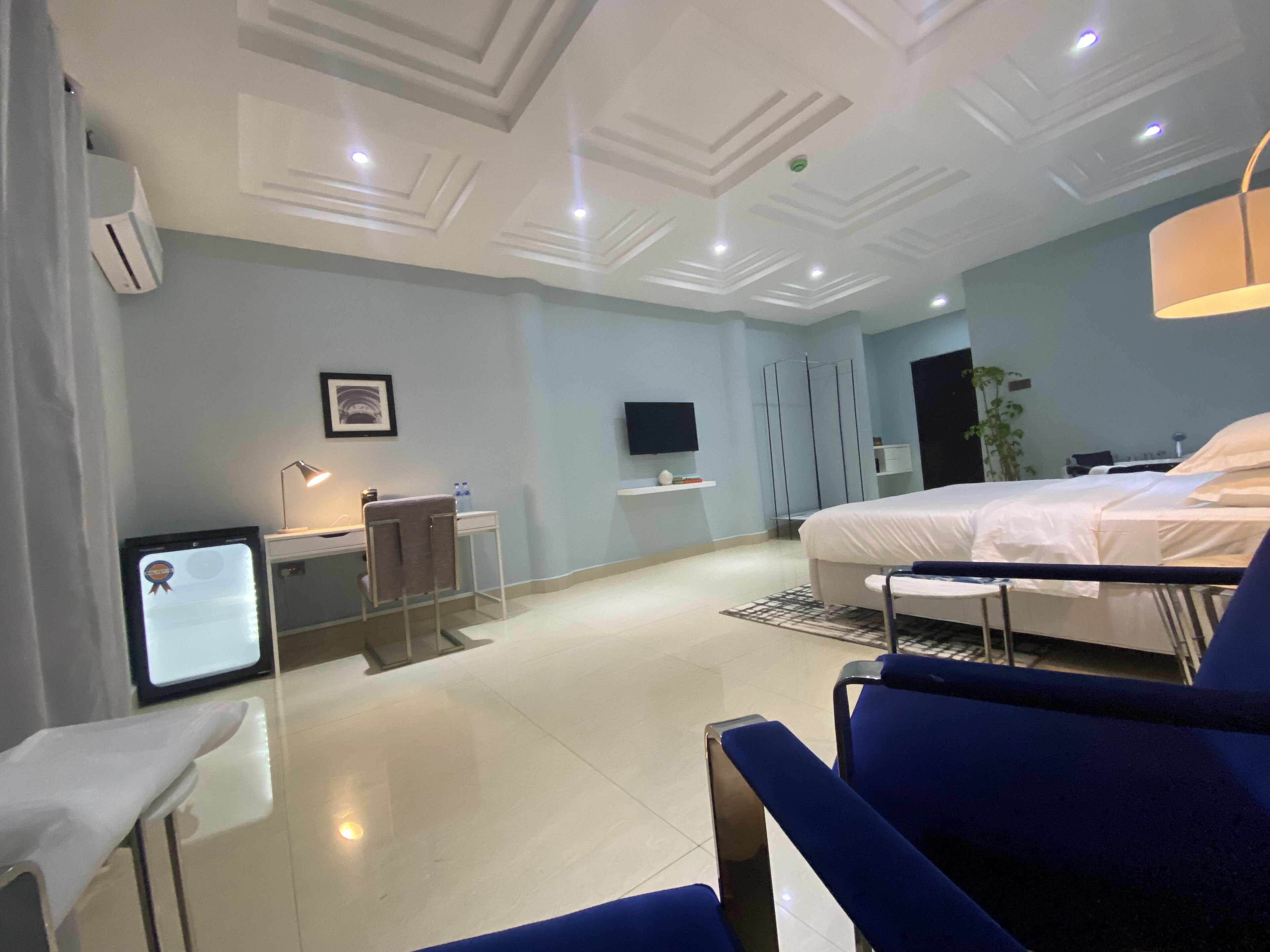 A modern hotel room with a bed, desk, chair, and a TV on the wall.