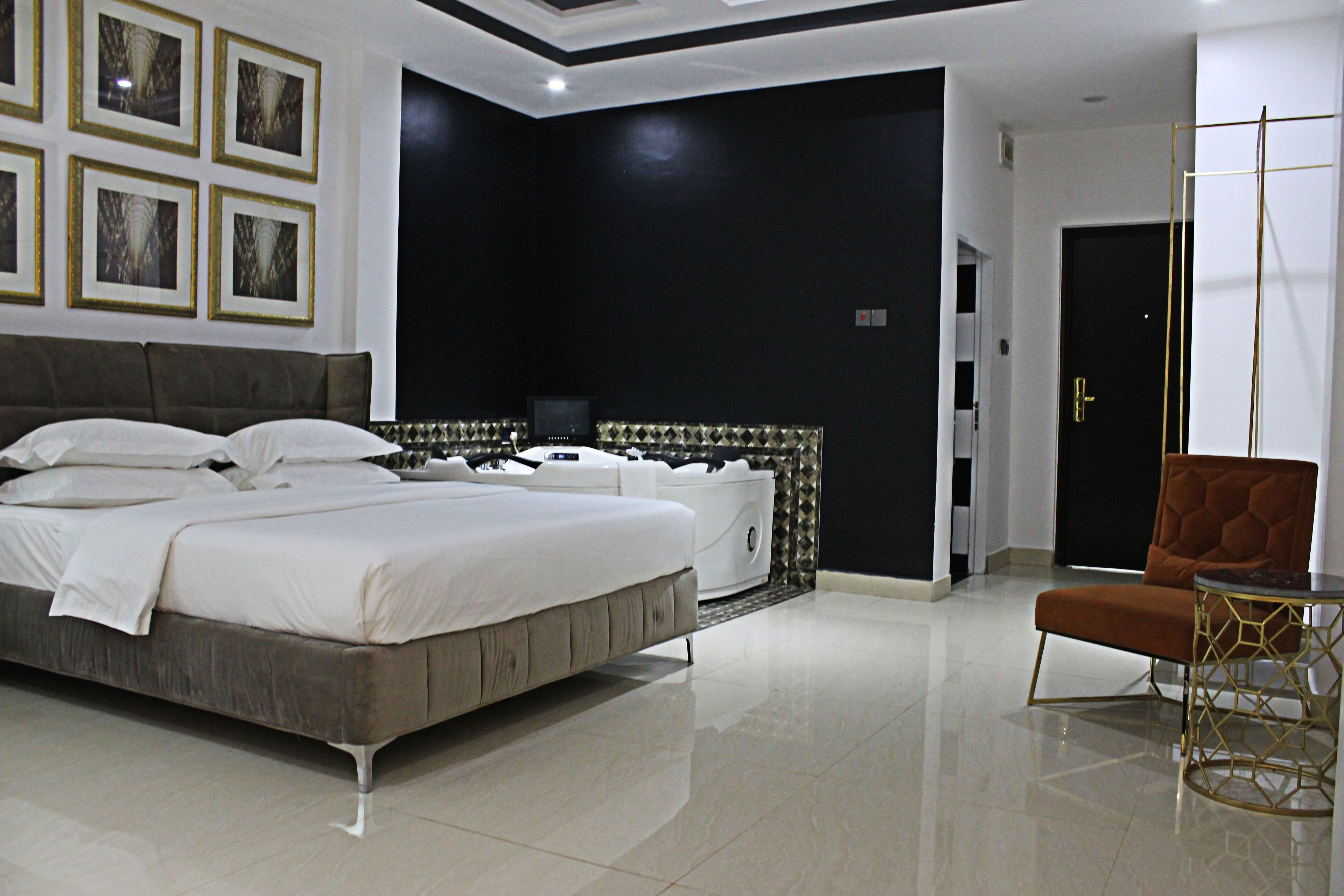 A modern bedroom with a large bed, a bedside table, a chair, and a TV.