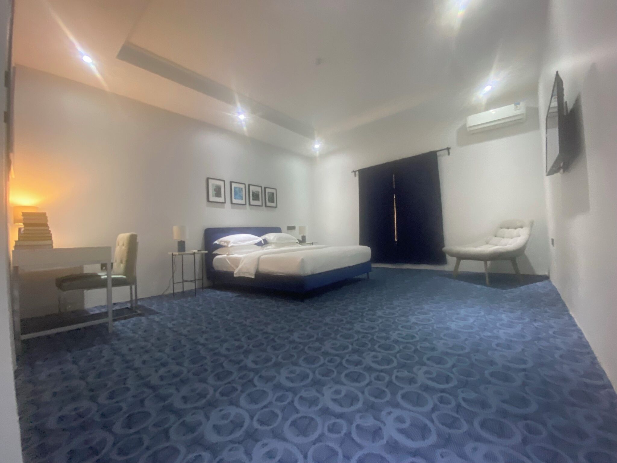 Une chambre d’hôtel équipée d’un lit, d’un bureau, d’une chaise, d’une armoire et d’un téléviseur fixé au mur.