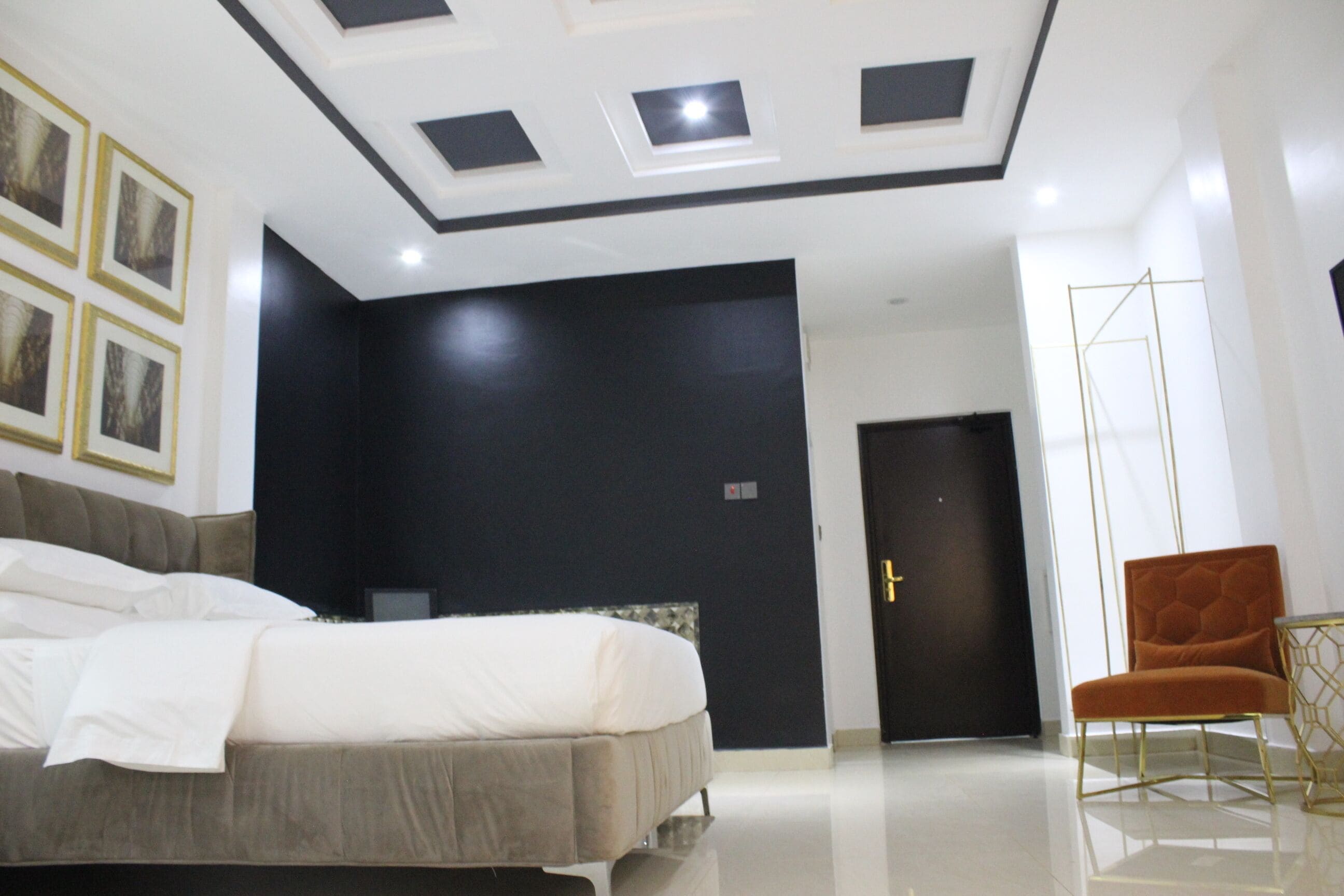 A modern bedroom with a bed, a chair, and a door.