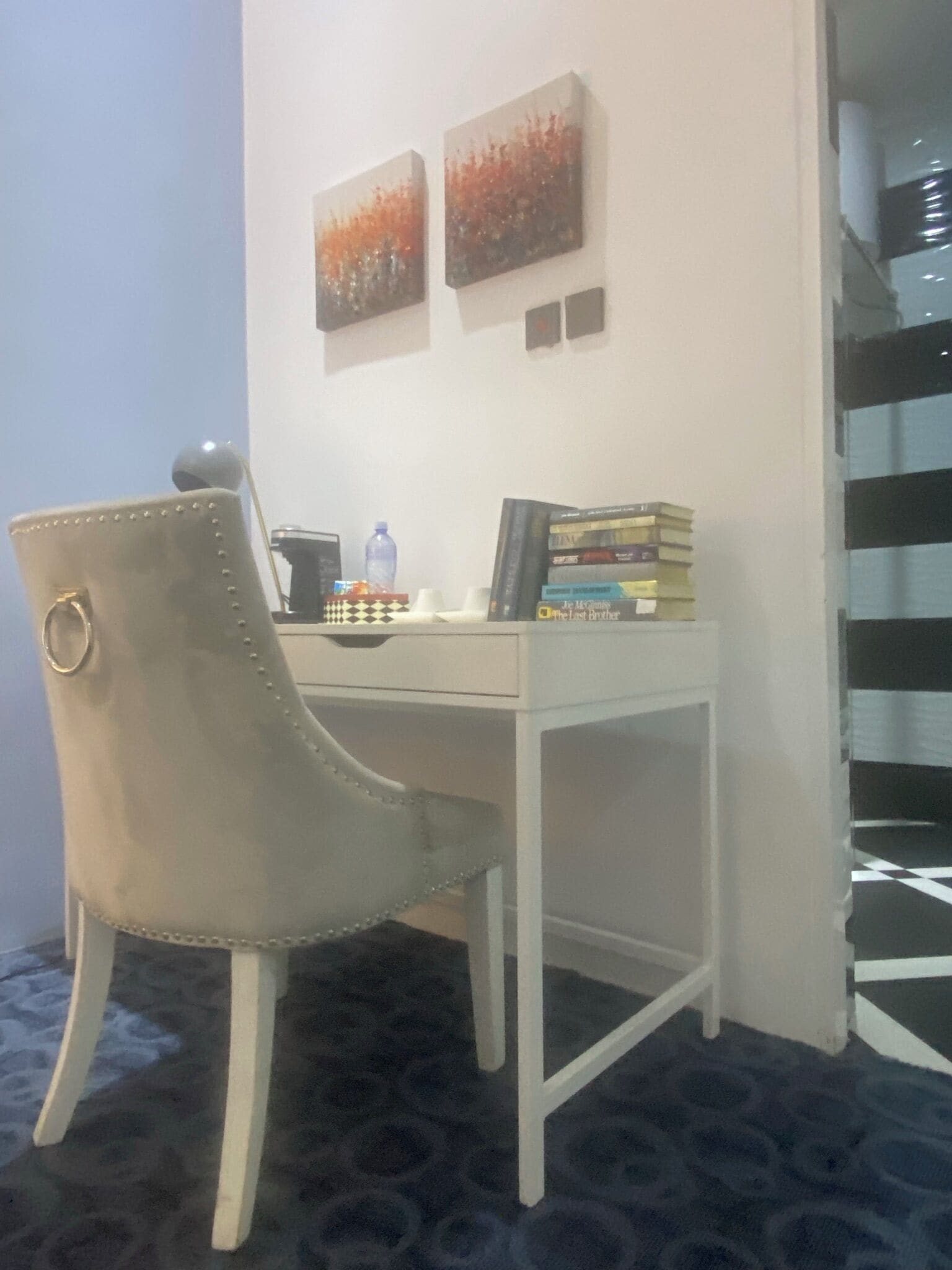 A corner office with a desk, chair, and two artworks on the wall.